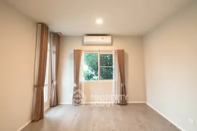 Spacious empty room with large window and air conditioning, perfect for customization.
