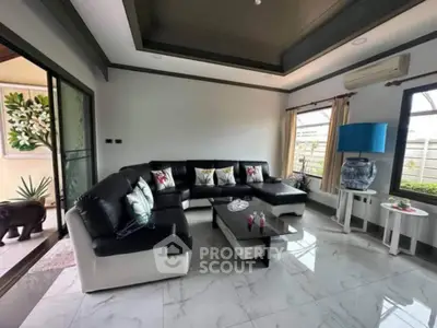 Spacious modern living room with sleek black and white furniture and large windows.