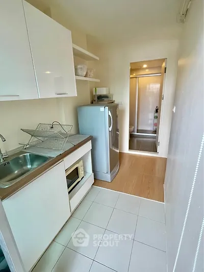 Compact kitchen with modern appliances and sleek cabinetry in a cozy apartment setting.