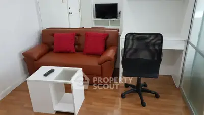 Cozy living room with brown sofa, red cushions, and modern office chair on wooden floor.