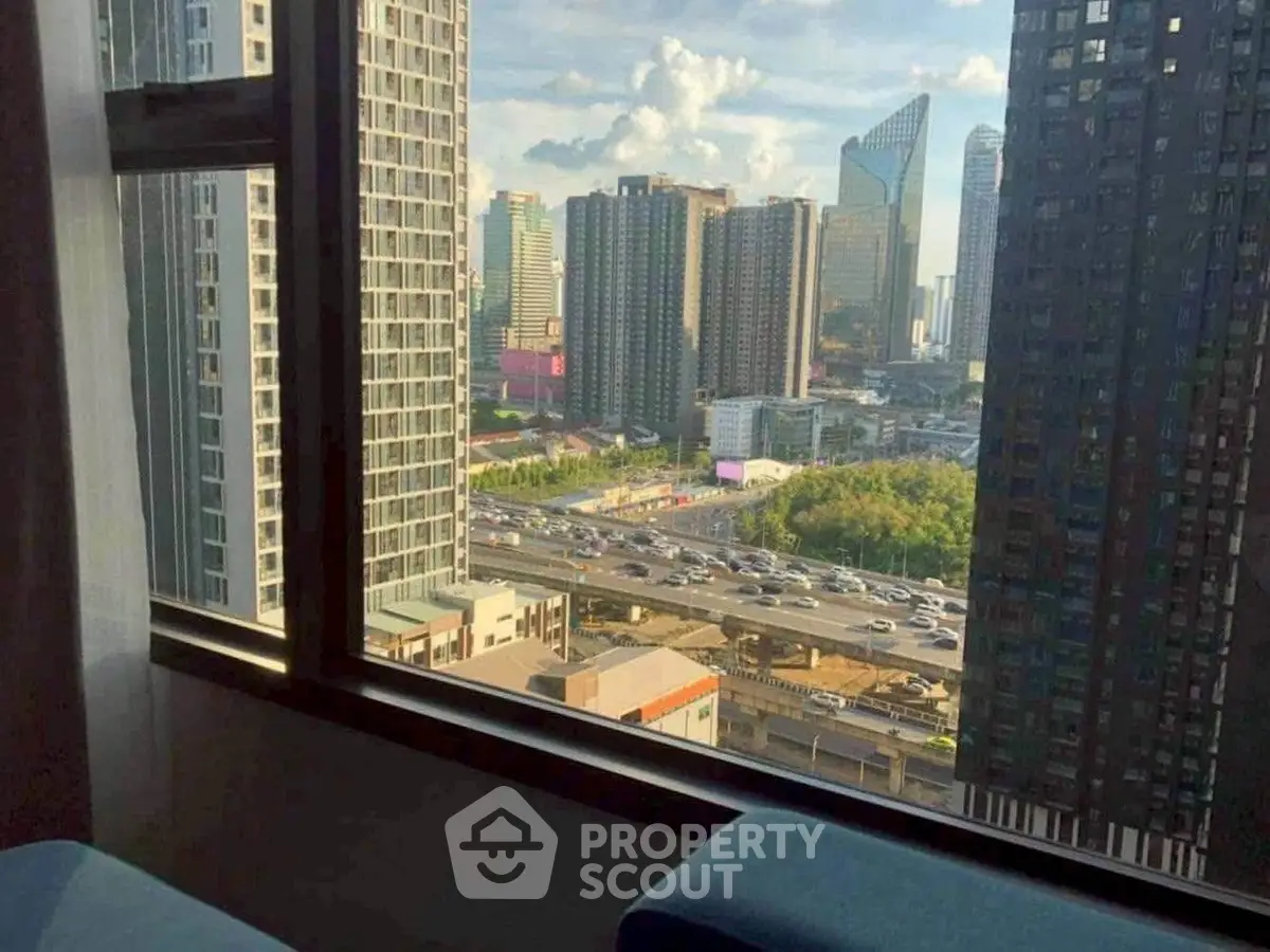 Stunning cityscape view from high-rise apartment window, showcasing urban skyline and bustling highway.