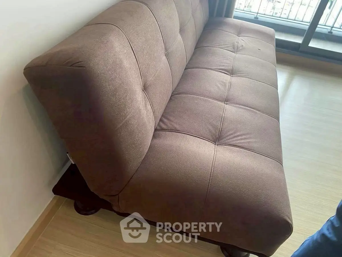 Modern brown sofa in a bright living room with wooden flooring and balcony view.