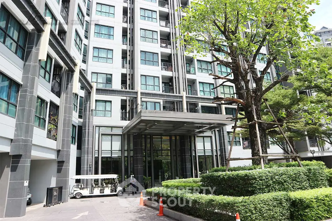 Modern condominium entrance with lush greenery and sleek architecture.