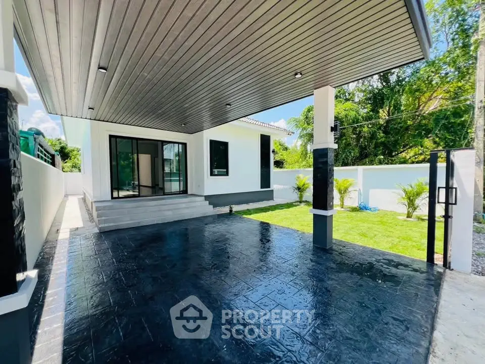 Modern single-story home with sleek exterior and spacious driveway, surrounded by lush greenery.