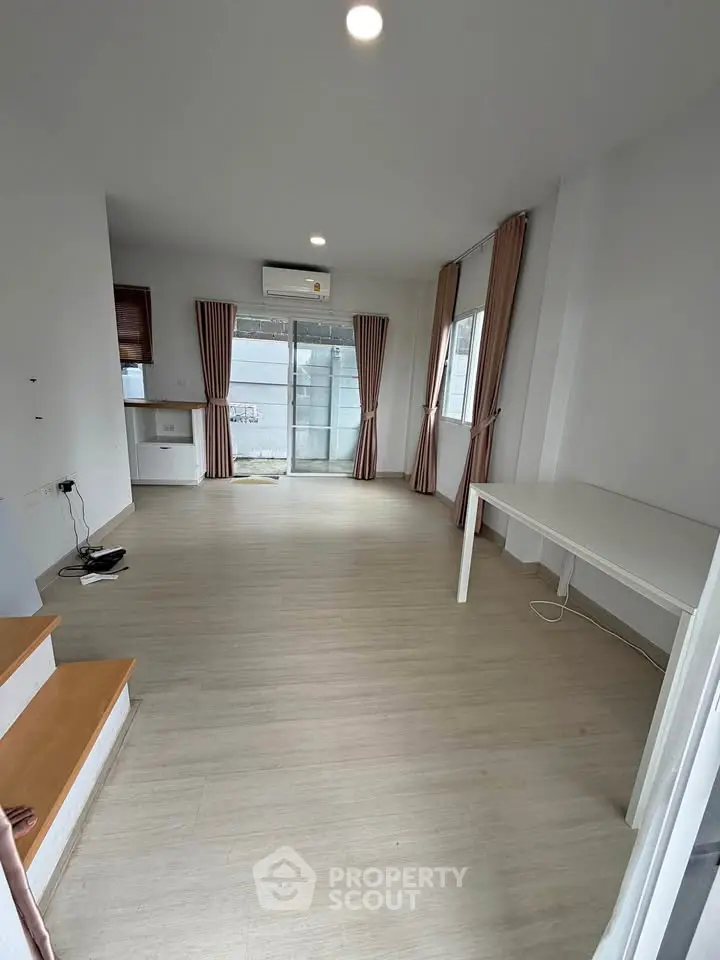 Spacious modern living room with large windows and wooden flooring, perfect for natural light lovers.