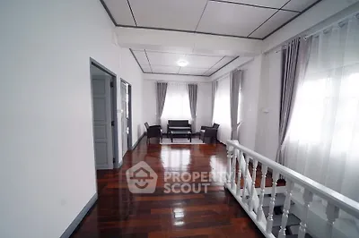 Spacious living area with polished wooden floors and elegant curtains
