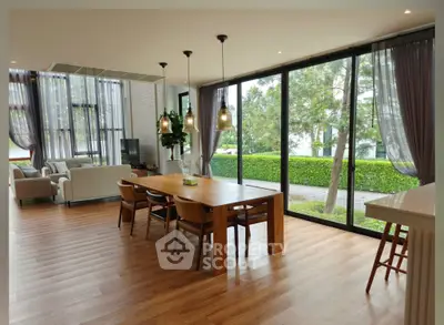 Spacious modern living room with large windows and garden view, featuring elegant dining area.