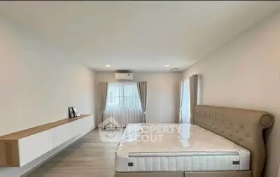 Spacious bedroom with elegant bed and modern decor in a bright, airy setting.