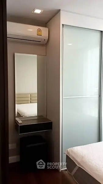 Modern bedroom with sleek design featuring air conditioning and sliding door closet.
