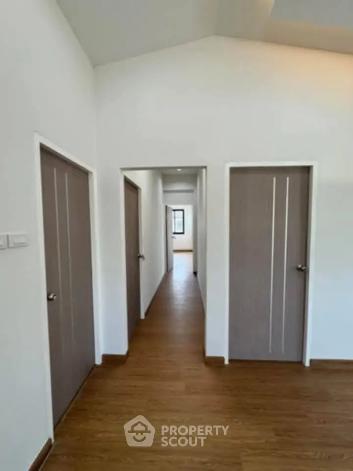 Spacious hallway with wooden flooring and modern doors in a contemporary home.