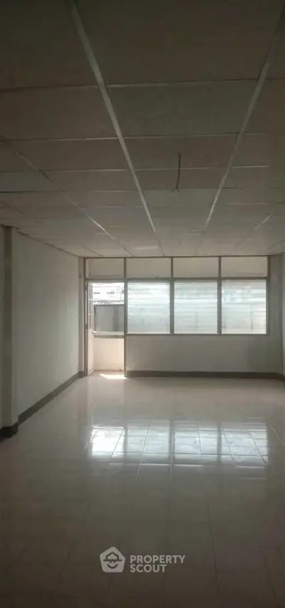 Spacious empty room with large windows and tiled floor, ideal for customization.