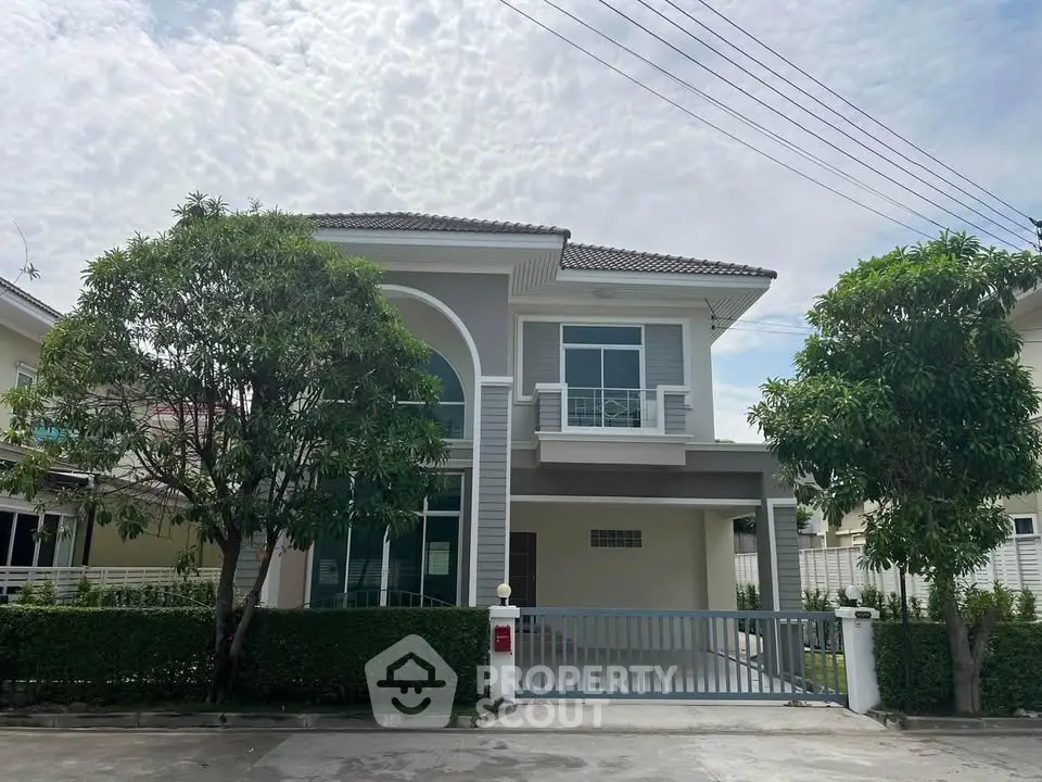Modern two-story house with gated driveway and lush greenery