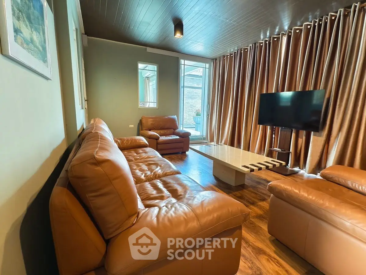 Spacious living room with leather sofas and modern TV setup, perfect for relaxation and entertainment.