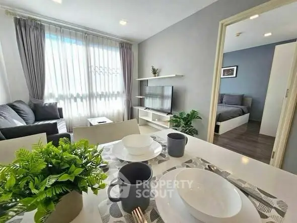 Modern living room with dining area and view into cozy bedroom, featuring stylish decor and natural light.