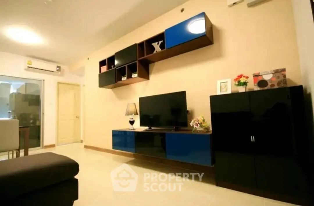 Spacious living room with modern entertainment unit, sleek furnishings, and warm ambient lighting leading to a cozy balcony.