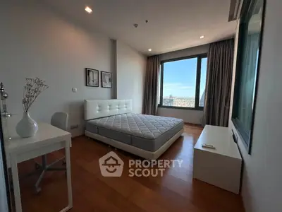 Spacious bedroom with large window offering stunning city views, modern furnishings, and elegant decor.