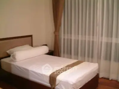 Cozy bedroom with single bed and elegant curtains, perfect for a peaceful retreat.