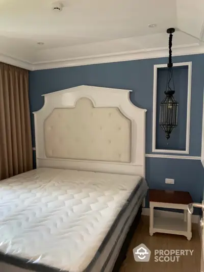 Elegant bedroom with a large bed featuring a stylish white headboard, serene blue walls, and a classic hanging lantern light fixture.