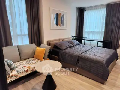 Modern bedroom with stylish decor and cozy seating area in a well-lit apartment.