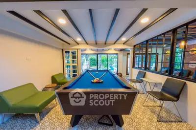 Stylish game room with pool table and modern seating in a bright, open space.