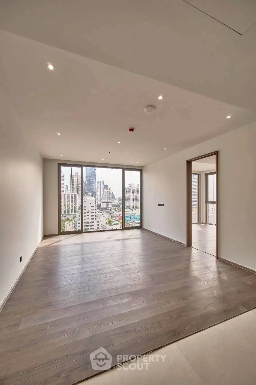 Spacious modern living room with large windows offering stunning city views in a high-rise apartment.