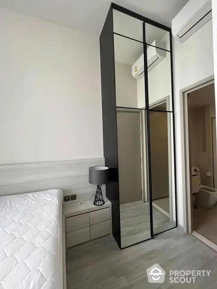 Modern bedroom with sleek mirrored wardrobe and air conditioning unit