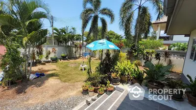 Charming tropical garden with lush greenery and patio area in a serene residential setting.