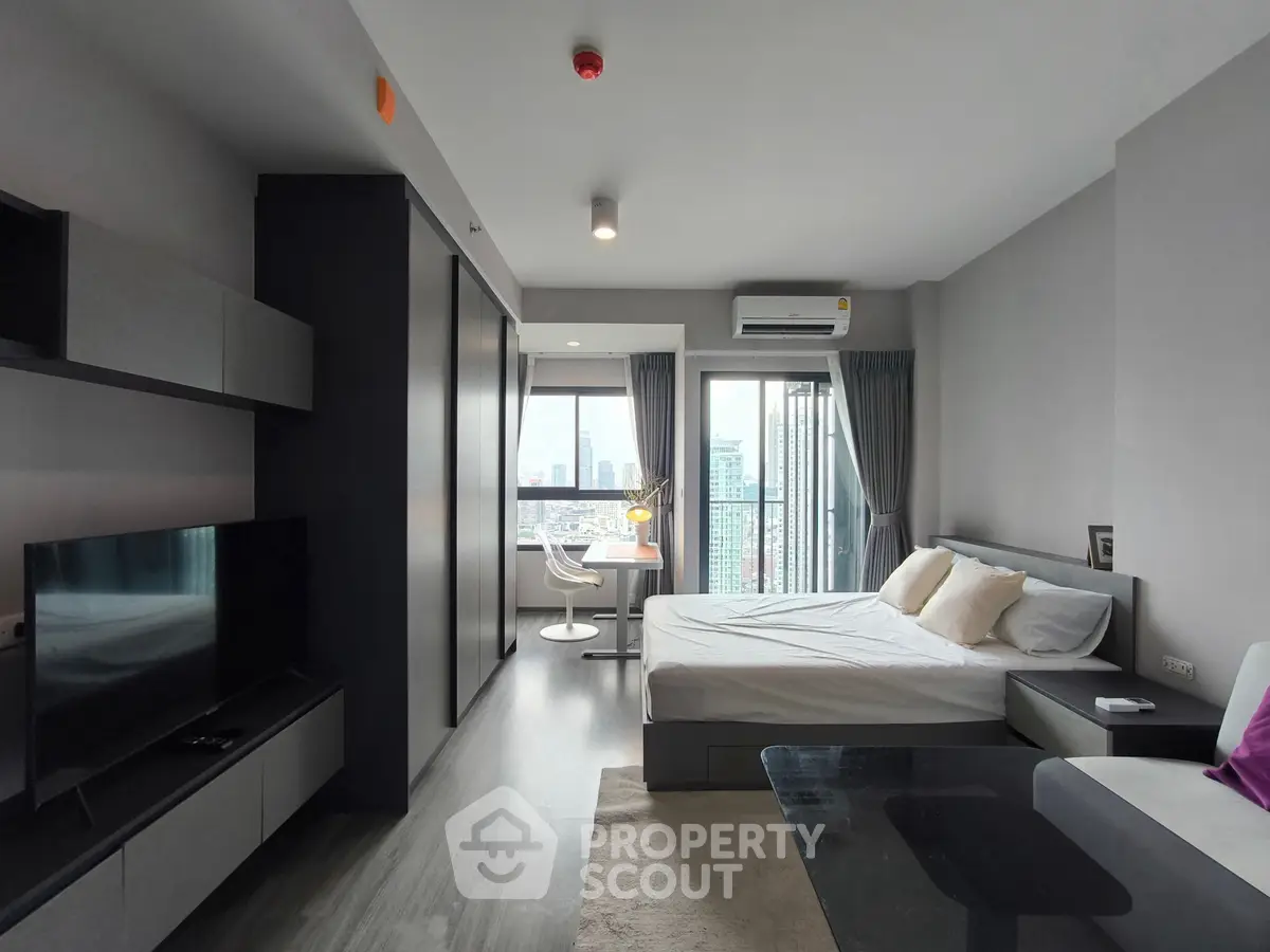 Modern studio apartment with city view, featuring sleek furniture and large windows for natural light.