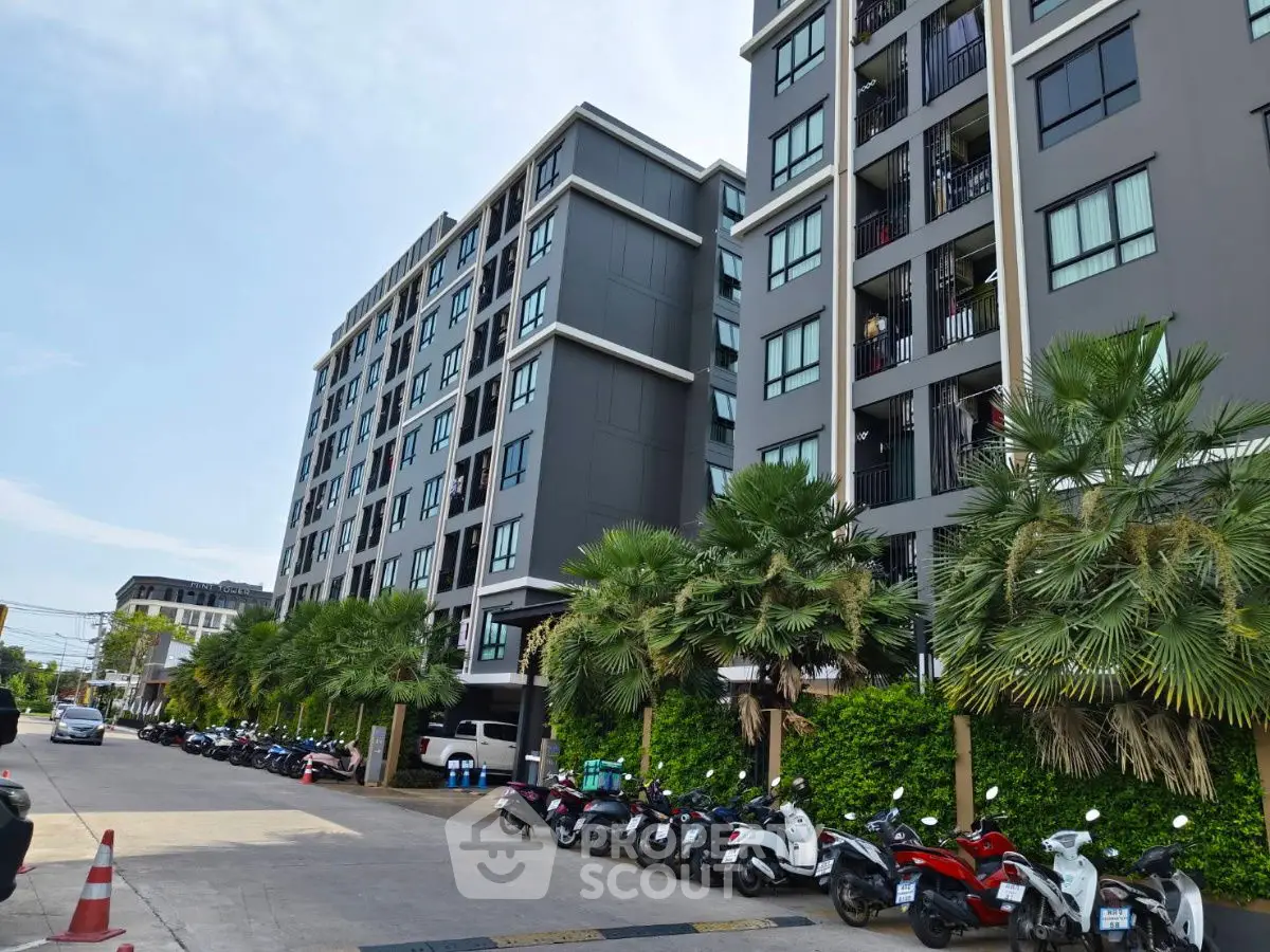 Modern apartment building with palm trees and parked scooters, urban living at its finest.