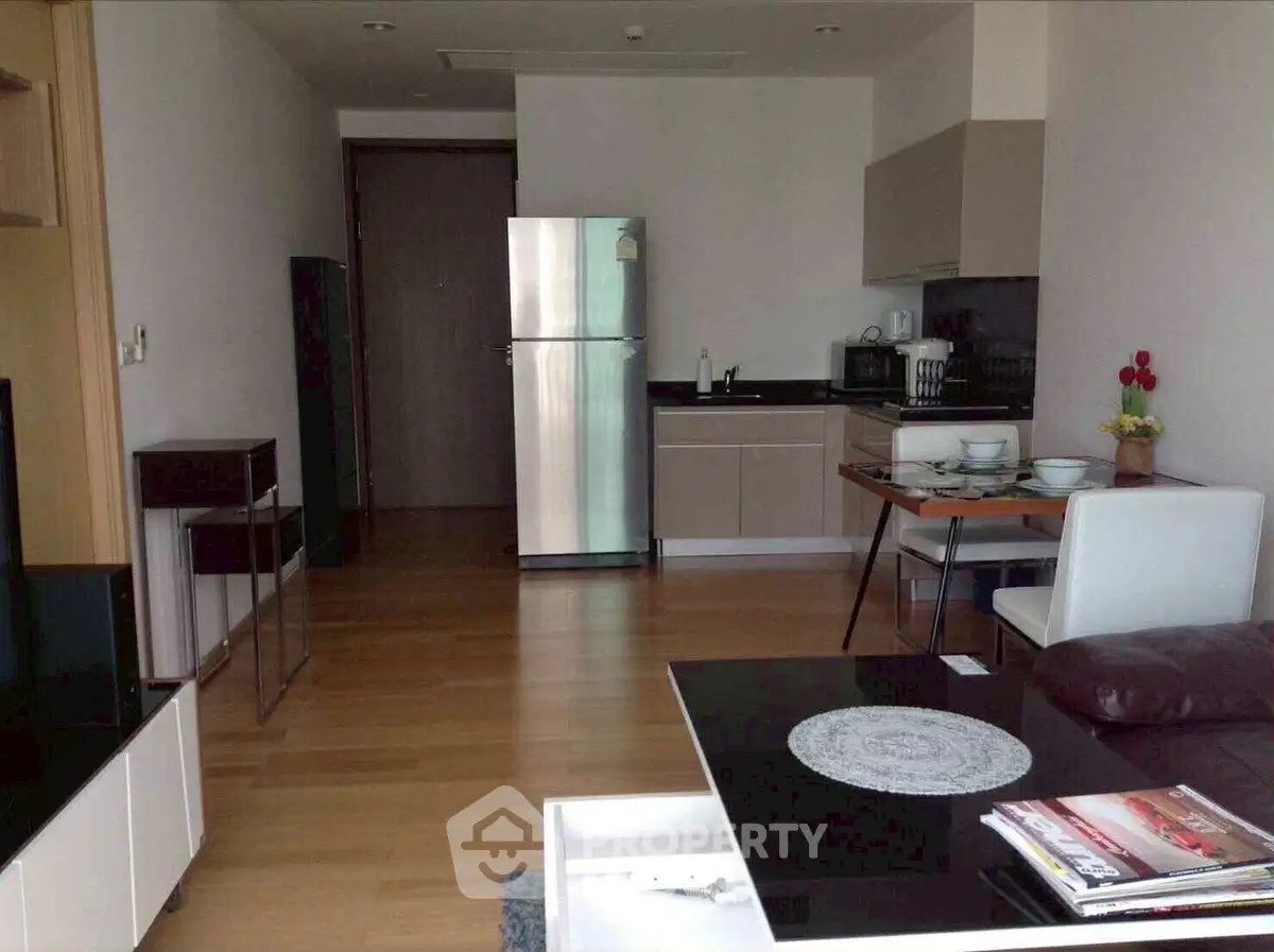Modern kitchen with sleek appliances and dining area in open layout apartment.