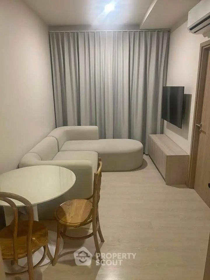 Cozy modern living room with stylish furniture and wall-mounted TV, perfect for relaxation.