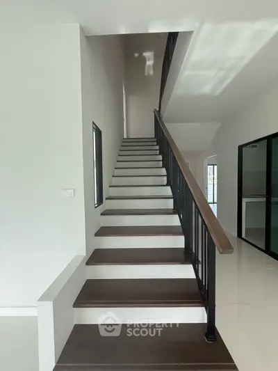 Modern staircase with sleek design and glass doors in a bright interior space.