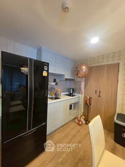 Modern kitchen with sleek black fridge and stylish cabinetry in cozy apartment.