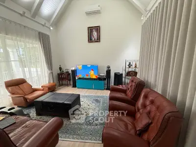 Spacious living room with high ceiling, leather sofas, and large TV, perfect for family gatherings.