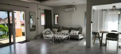 Spacious modern living room with elegant decor and abundant natural light, featuring a stylish sofa and dining area.
