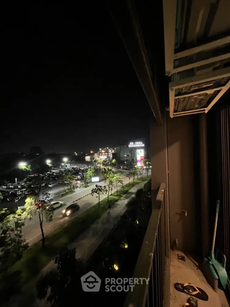 Night view from a balcony overlooking a busy street and parking area.