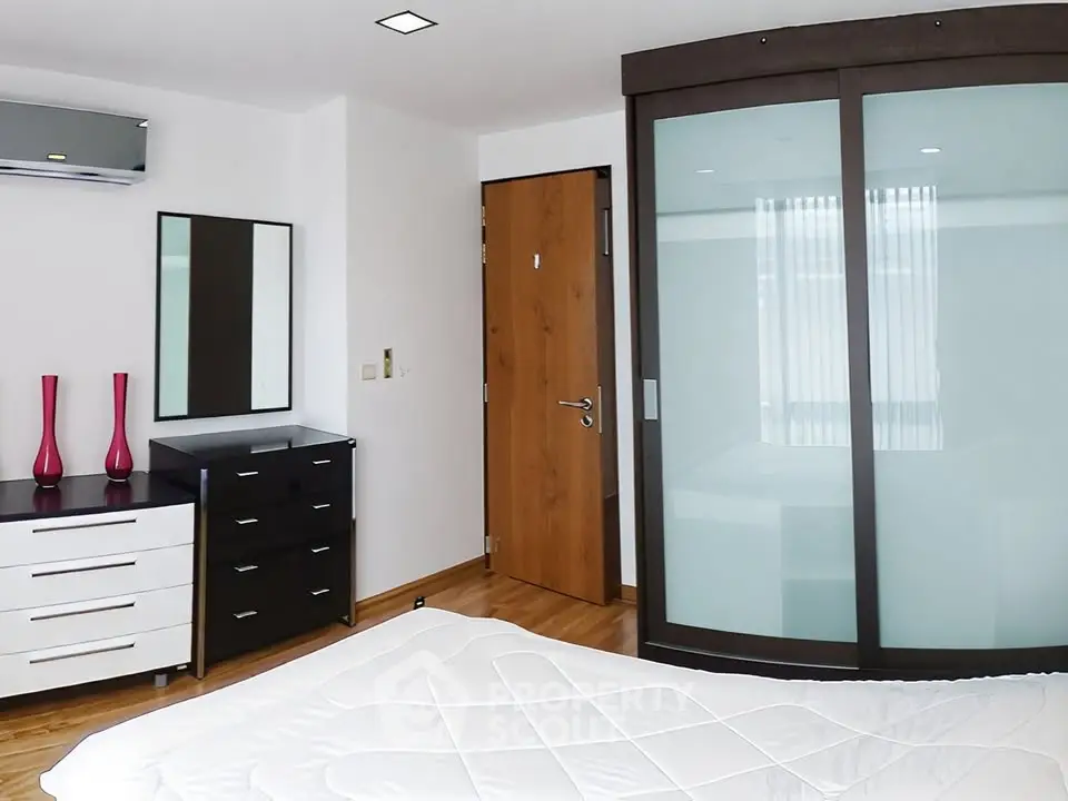 Modern bedroom with sleek furniture and frosted glass wardrobe