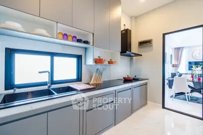 Modern kitchen with sleek cabinetry and open layout leading to dining area.