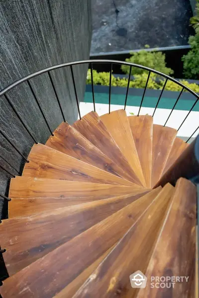 Elegant spiral staircase with wooden steps and black railing in modern home