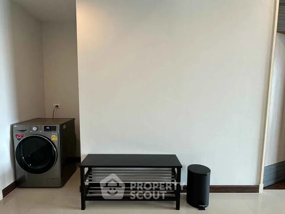 Modern laundry area with washing machine and sleek black furniture in a minimalist home setting.