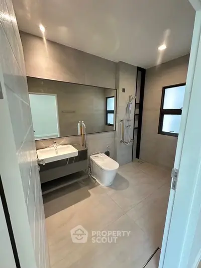 Modern bathroom with sleek fixtures and minimalist design, featuring a spacious shower and elegant sink.