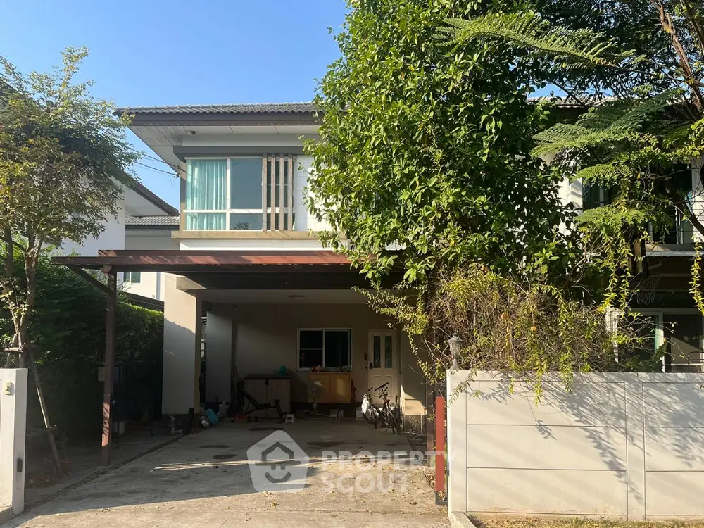 Charming two-story house with lush greenery and spacious driveway in a serene neighborhood.
