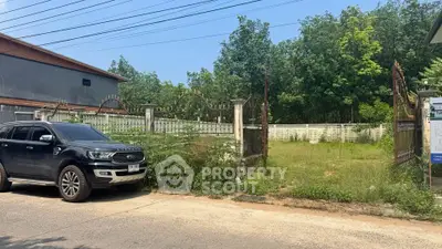 Vacant land plot with gated entrance and lush greenery, ideal for development opportunities.