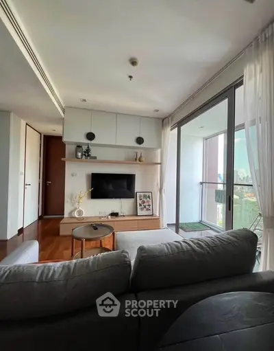 Modern living room with balcony view, stylish decor, and natural light in urban apartment.