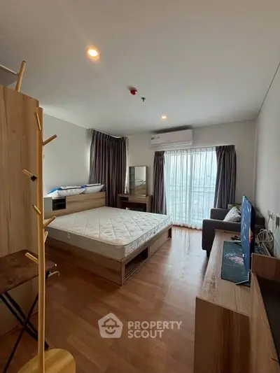 Spacious bedroom with modern furnishings and large window offering natural light.