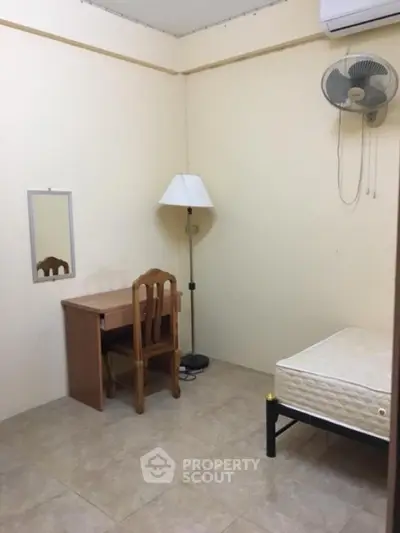 Cozy minimalist bedroom with desk, chair, and wall-mounted fan for comfort.