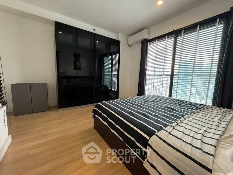 Modern bedroom with striped bedding and large windows offering natural light