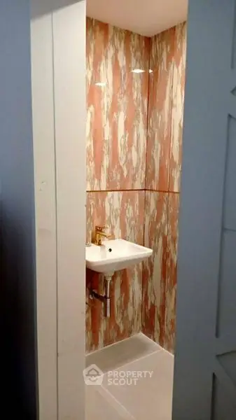 Compact bathroom with stylish marble-patterned walls and modern sink.