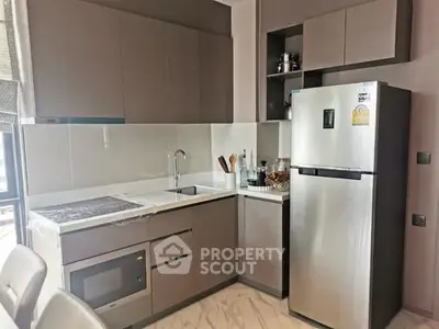 Modern kitchen with sleek cabinets, built-in oven, and stainless steel fridge in a stylish apartment.