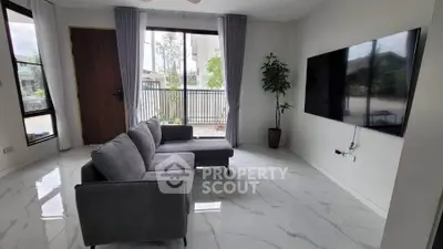Modern living room with sleek gray sofa and large wall-mounted TV, featuring elegant marble flooring.